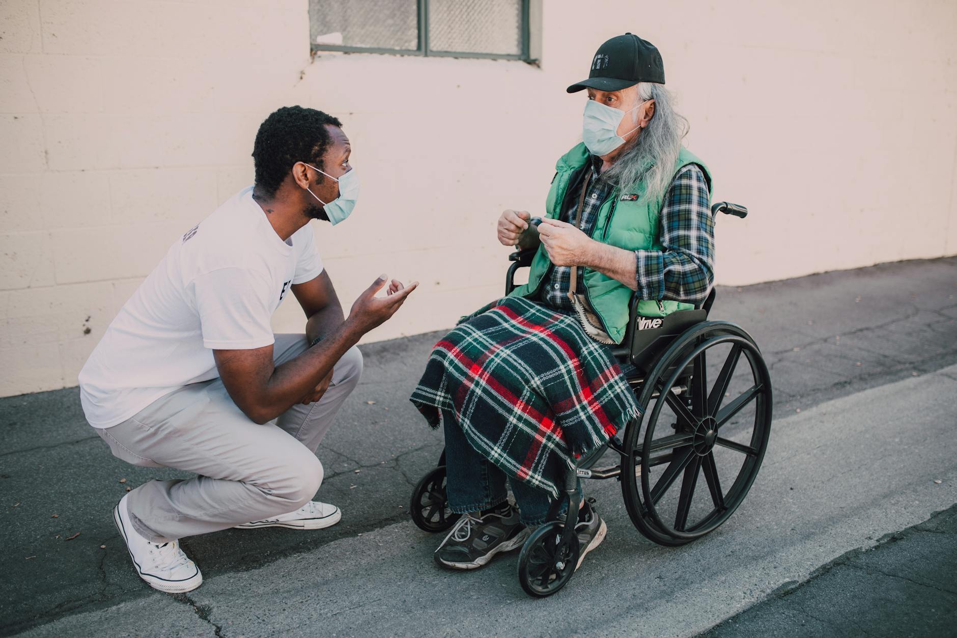 a man talking to an elderly man sitting on a wheelchair